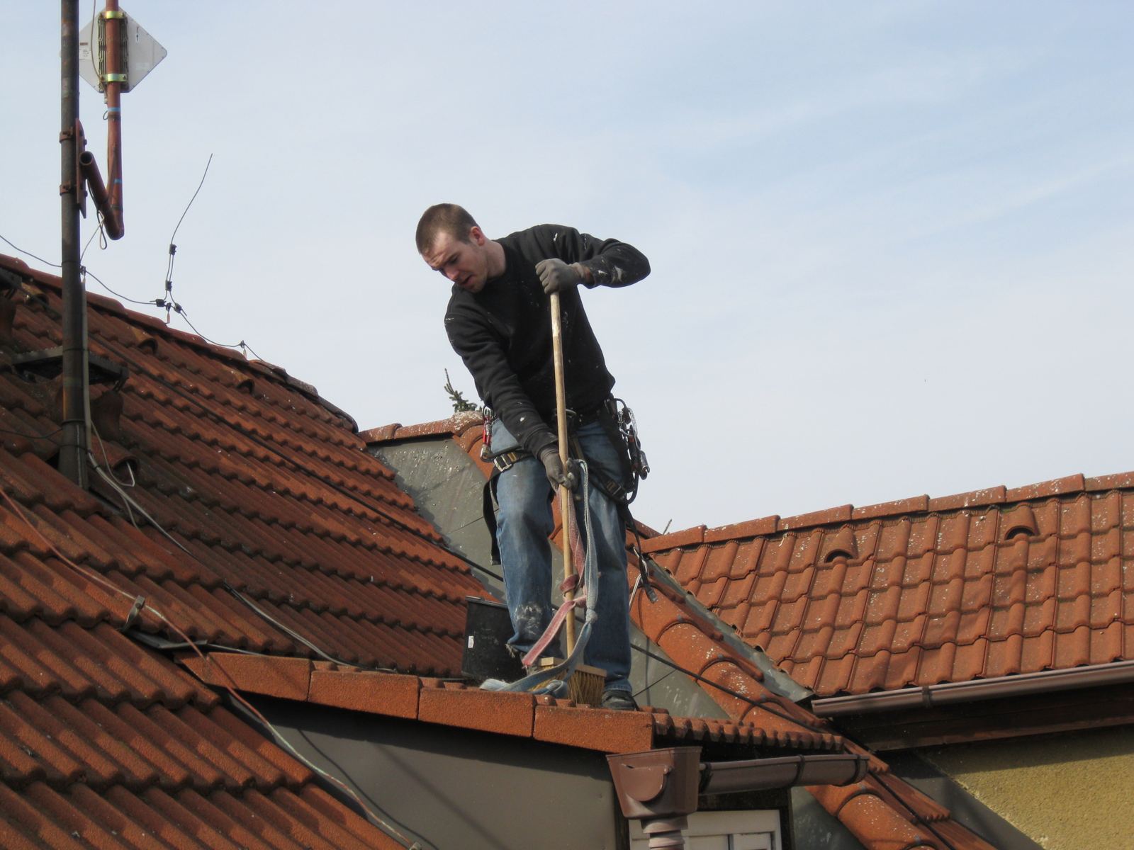 Klempíř na hřebeni střechy jištěný lanem